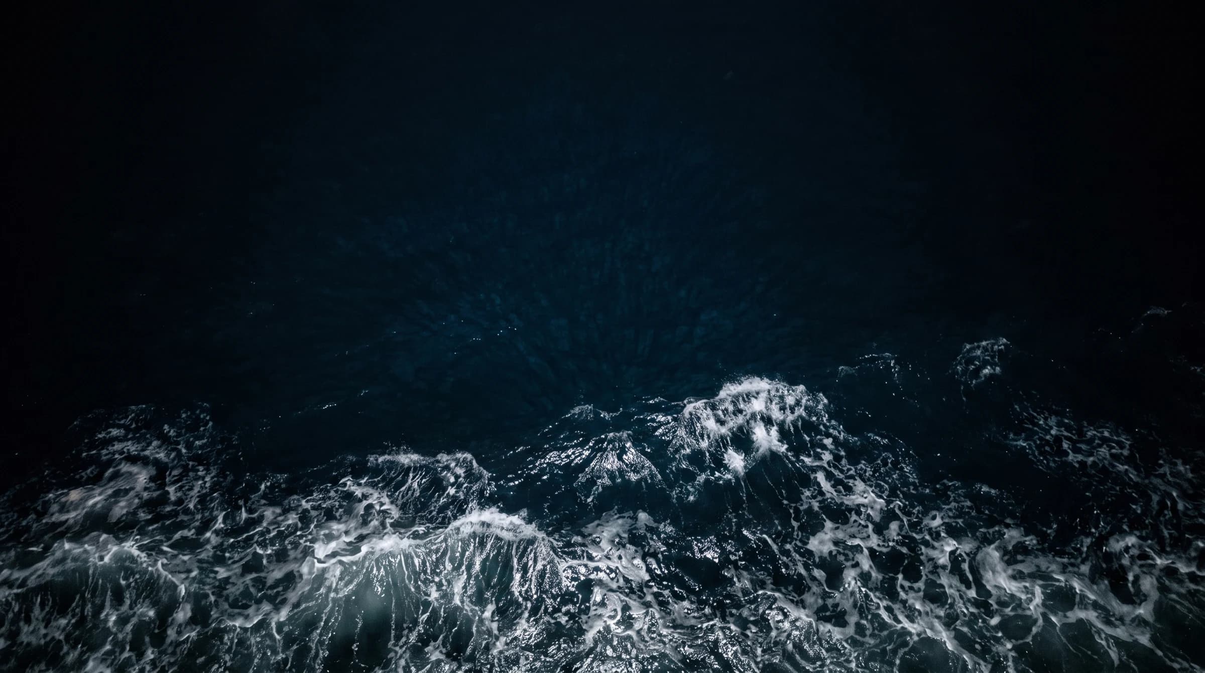 North Atlantic water seen from above, breaking white across the lower half of the frame.